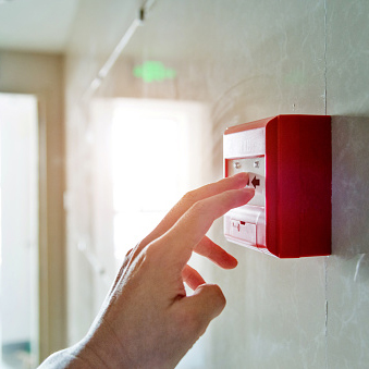 foto de uma pessoa acionando botoeira de alarme de incendio